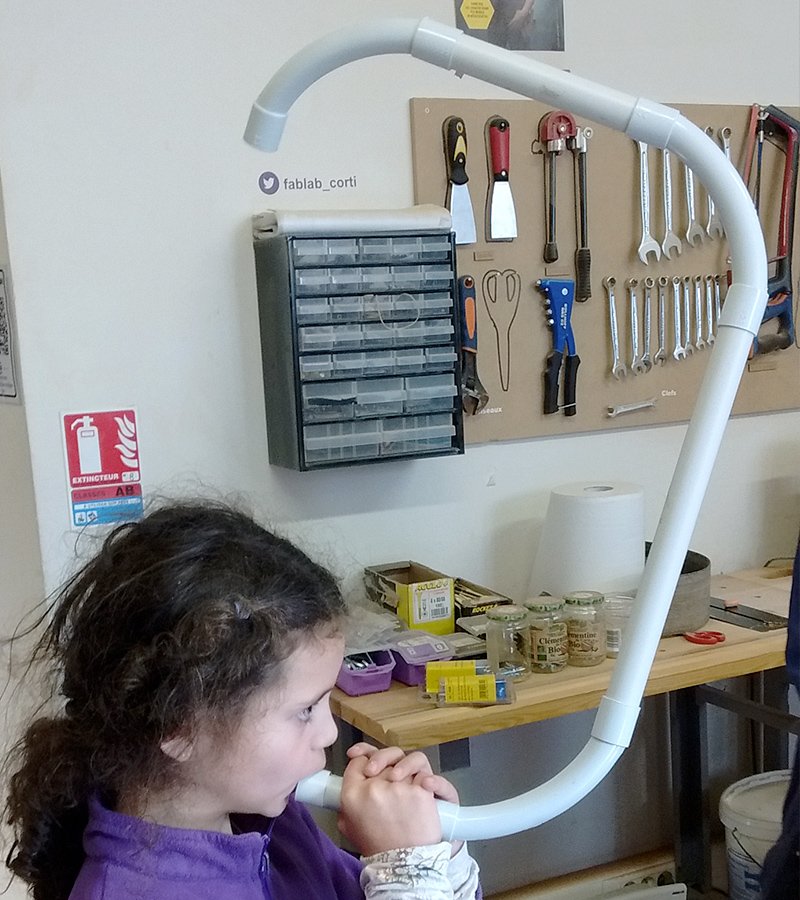 Enfant jouant d'une grande flûte harmonique en tubes, au fablab