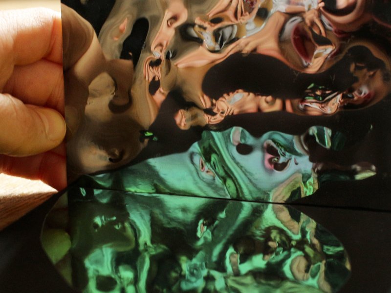 Reflets colorés déformés dans un miroir souple tenu à la main