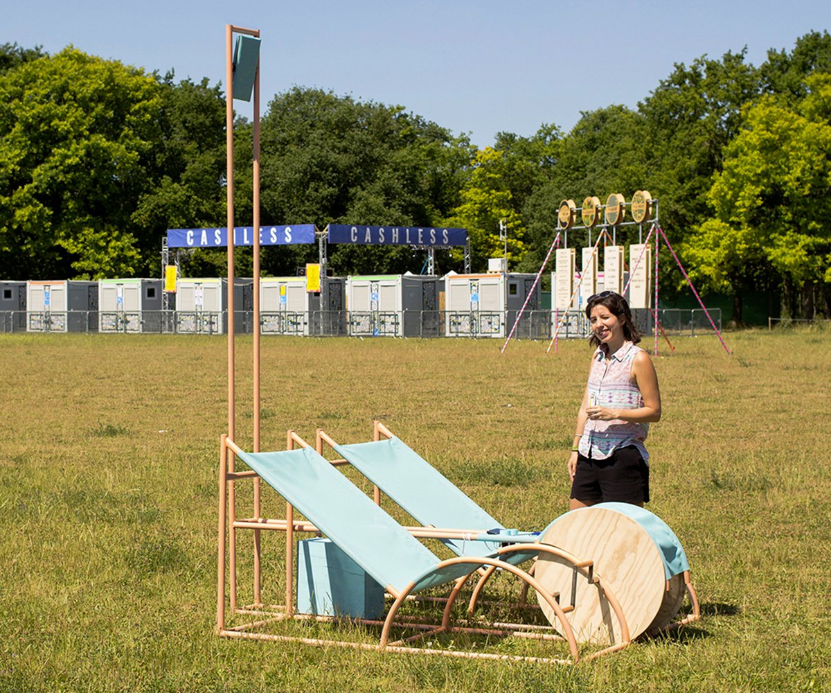Pédalo dynamo sur la pelouse d'un festival : deux transats bleus à pédales, une roue en bois et un mât lumineux